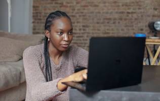 A woman is efficiently utilising her laptop to navigate through the system for knowledge management.